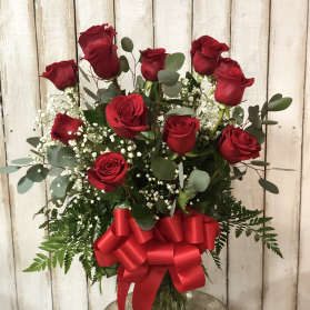 Red roses in a glass vase with a large red bow
