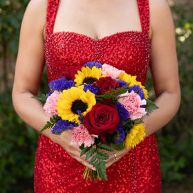 Woman holding a bouquet of red roses, sunflowers, pink carnations, and purple filler flowers