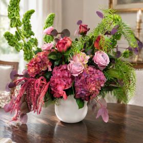 Pink and purple floral arrangement in a white vase