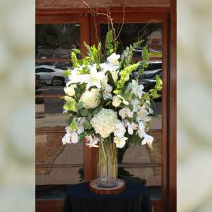 Tall white floral arrangement in a clear glass vase