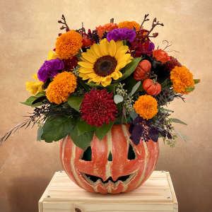 Sunflower and mixed fall flowers arranged in a carved pumpkin container