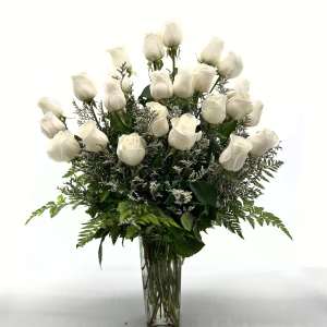White roses arranged in a tall glass vase with greenery