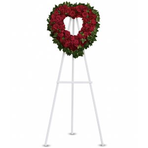 Heart-shaped wreath of red roses bordered with greenery on a white standing easel