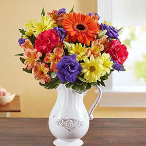 Colorful bouquet of mixed flowers in a white pitcher vase