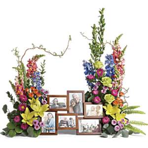 Colorful floral display with framed photos arranged between two tall sprays