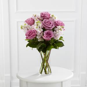 Pink roses and white filler flowers in a clear glass vase