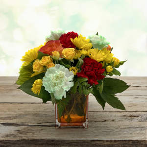 Mixed bouquet of yellow, red, orange, and white flowers in an amber glass vase