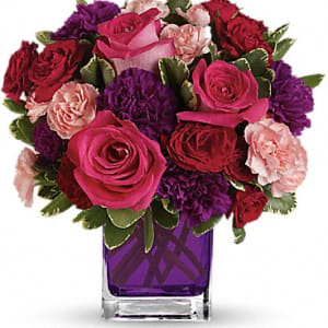 Pink and red roses with purple carnations in a purple glass vase