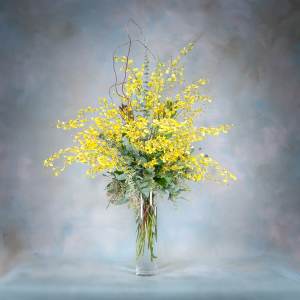 Tall yellow floral arrangement in a clear glass vase