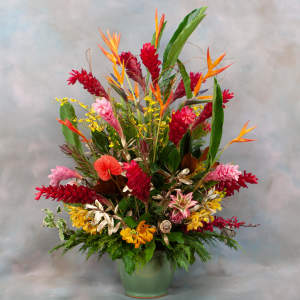 Tropical flower arrangement in a green vase with red, orange, and yellow blooms