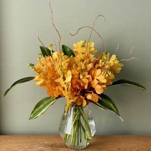 Orange and yellow orchid arrangement in a clear glass vase