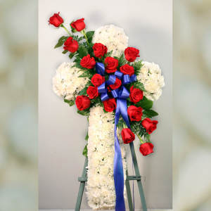 Standing floral cross of white flowers and red roses with a blue ribbon