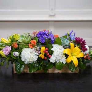 Colorful mixed flower arrangement in a low wooden box