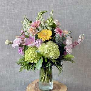 Mixed bouquet with pink, yellow, and green flowers in a glass vase