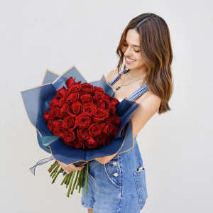 Woman holding a bouquet of red roses wrapped in blue paper