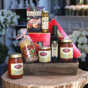 Italian-themed gourmet gift set with pasta, sauces, and olive oil arranged in a wooden tray.
