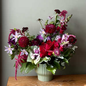 Mixed bouquet of red, pink, and lavender flowers in a ribbed vase