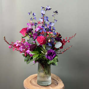 Colorful bouquet of purple, pink, and blue flowers in a glass vase