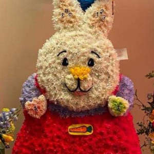 Flower-covered bunny figure with balloons above it