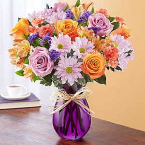 Mixed bouquet of roses, daisies, and alstroemeria in a purple vase