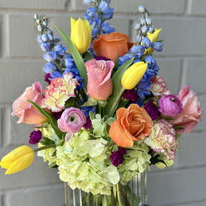 Colorful mixed bouquet in a clear glass vase with roses and tulips