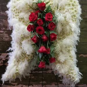 Standing funeral spray of red roses on a white feathered wreath