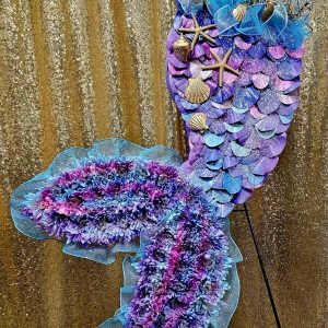 Purple and blue mermaid-shaped floral display with shells and starfish
