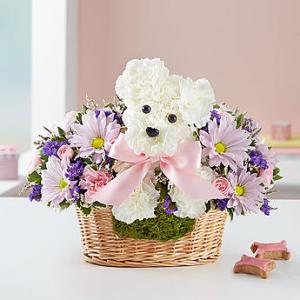 White teddy bear floral arrangement in a wicker basket with pink ribbon
