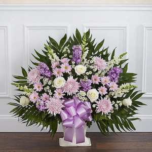Lavender and white floral arrangement with a purple ribbon in a white vase