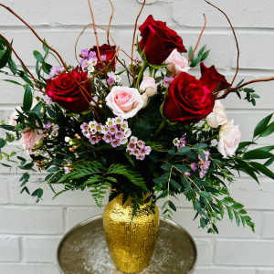 Bouquet of red and pale pink roses in a gold vase