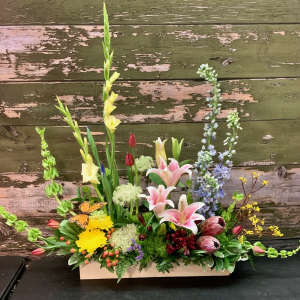 Mixed floral arrangement in a rectangular wooden box with lilies and tall spikes