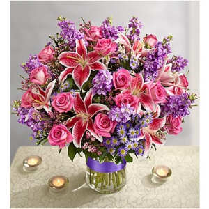 Pink roses and lilies with purple flowers in a glass vase