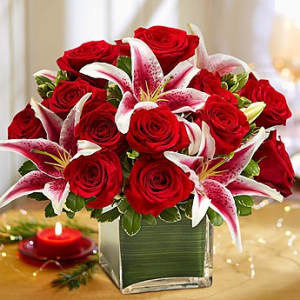 Red roses and pink lilies arranged in a square glass vase