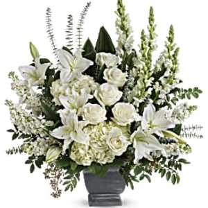 Tall white arrangement of lilies, roses, and hydrangeas in a gray pedestal vase