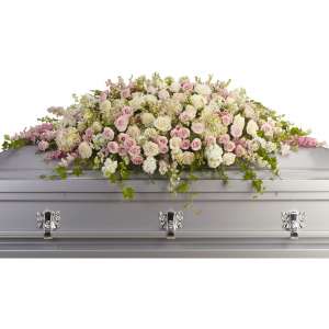 Large pastel pink and white rose casket spray draped across a silver casket
