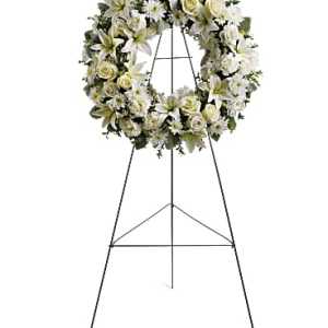 Standing wreath of white lilies, roses, and mums on a metal easel