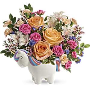 Peach and pink rose arrangement with lilies in a white ceramic unicorn container