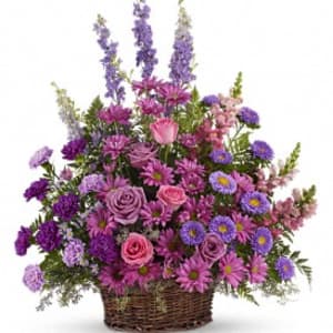 Lavender and purple mixed flower arrangement with roses and daisies in a woven basket