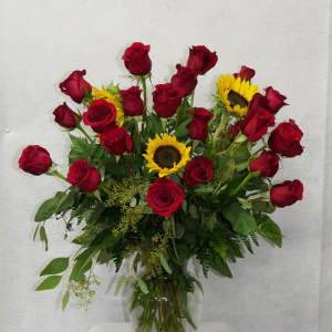 Red roses and sunflowers arranged in a clear glass vase