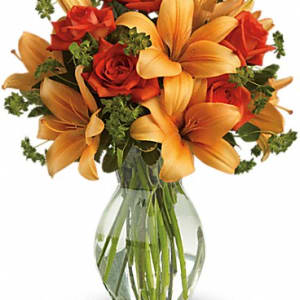 Bouquet of orange lilies and red roses in a clear glass vase