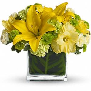 Yellow lilies and white flowers in a square glass vase
