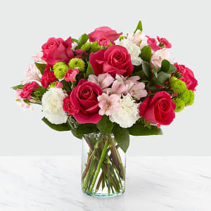 Pink and white bouquet of roses, carnations, and alstroemeria in a glass vase