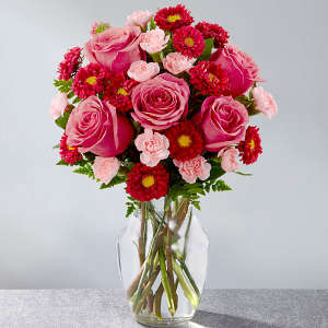 Pink roses and red daisy flowers in a clear glass vase