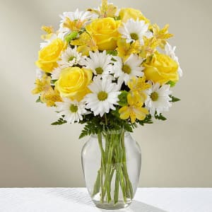 Yellow roses and white daisies in a clear glass vase