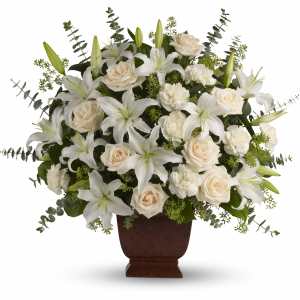 White lilies, roses, and carnations arranged in a brown pedestal vase