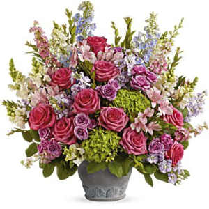 Abundant pink and purple mixed flower arrangement with green hydrangeas in a gray ceramic pot