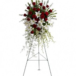 Tall standing spray of red roses and white lilies on a metal easel