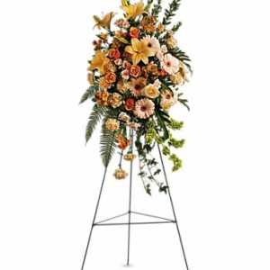 Tall standing spray of peach and yellow flowers on a metal easel.