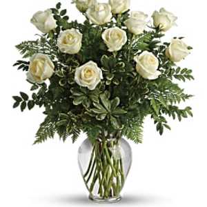 Bouquet of white roses with lush greenery in a clear glass vase