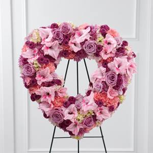 Heart-shaped floral wreath in pink and purple tones on a black stand